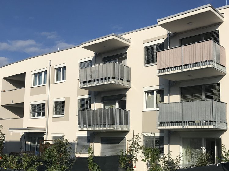A modern three-storey residential complex with gardens and balconies